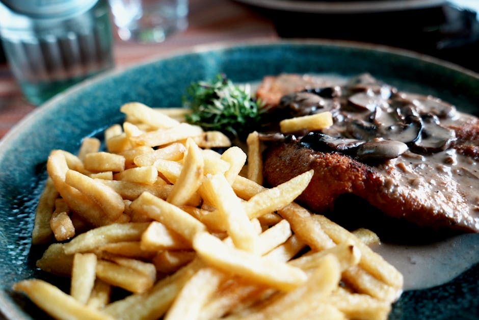 Appetizing schnitzel topped with mushroom sauce and served with crispy French fries.